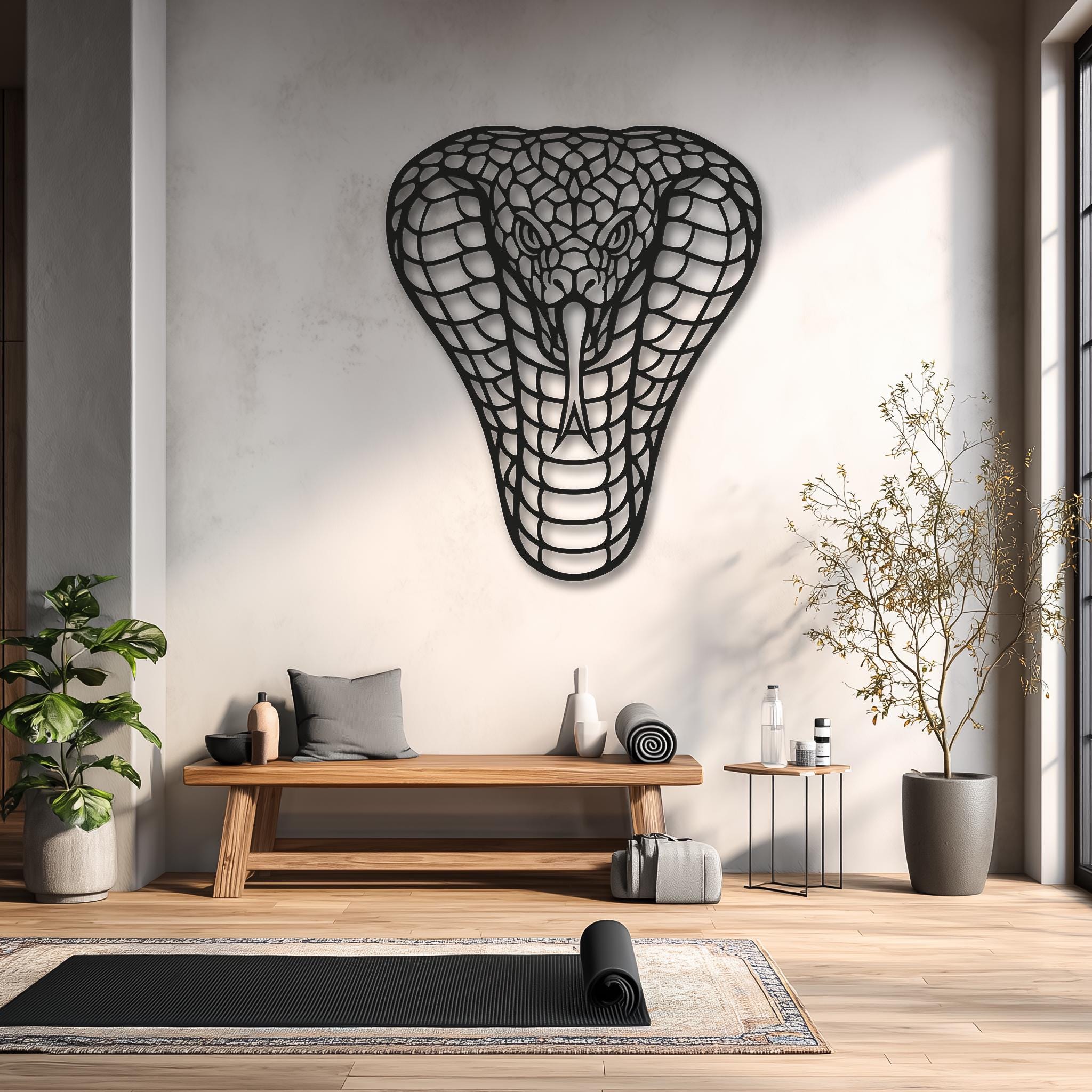 Cobra metal wall art in a calm studio/yoga corner; light wood bench and greenery; black powder-coated steel; minimalist lifestyle image; unique gift and XL wall decor