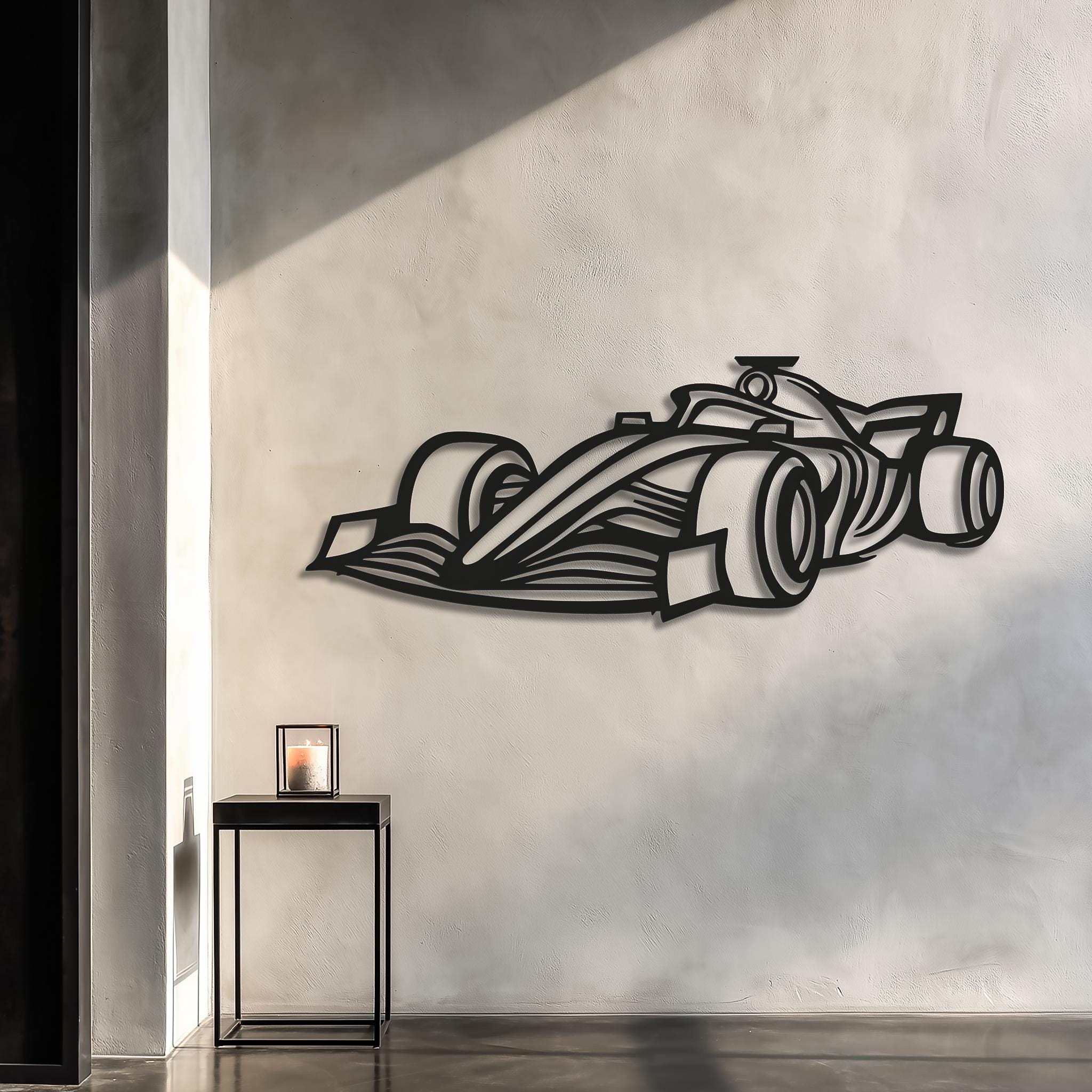 Open-wheel race car metal wall art in matte-black, CNC laser-cut, casting a 3D shadow on a sunlit plaster wall. Modern minimal hallway scene with small black side table. Motorsports racing decor, ready to hang, multiple sizes; personalize with driver name or number—gift for motorsport fans.
