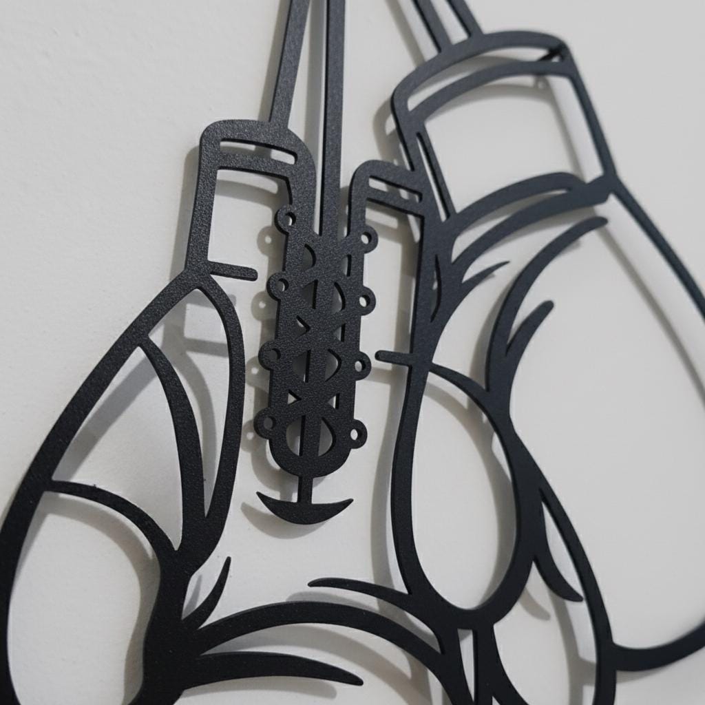 May include: A black metal wall art piece shaped like a pair of hanging boxing gloves. The design features clean outlines and a lace-up detail on one glove, with the word CUSTOM clearly visible on the wrist cuff of the other glove.