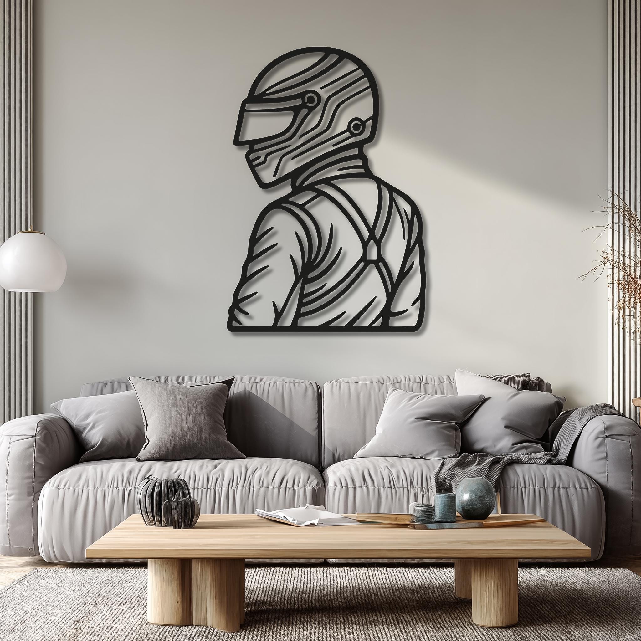 Motorsports race driver with helmet and harness, side profile; CNC metal wall art above a gray sofa; clean modern interior with soft light; bold outline; great for living room, office or teen room; racing fan gift; multiple sizes; easy to hang, durable finish.