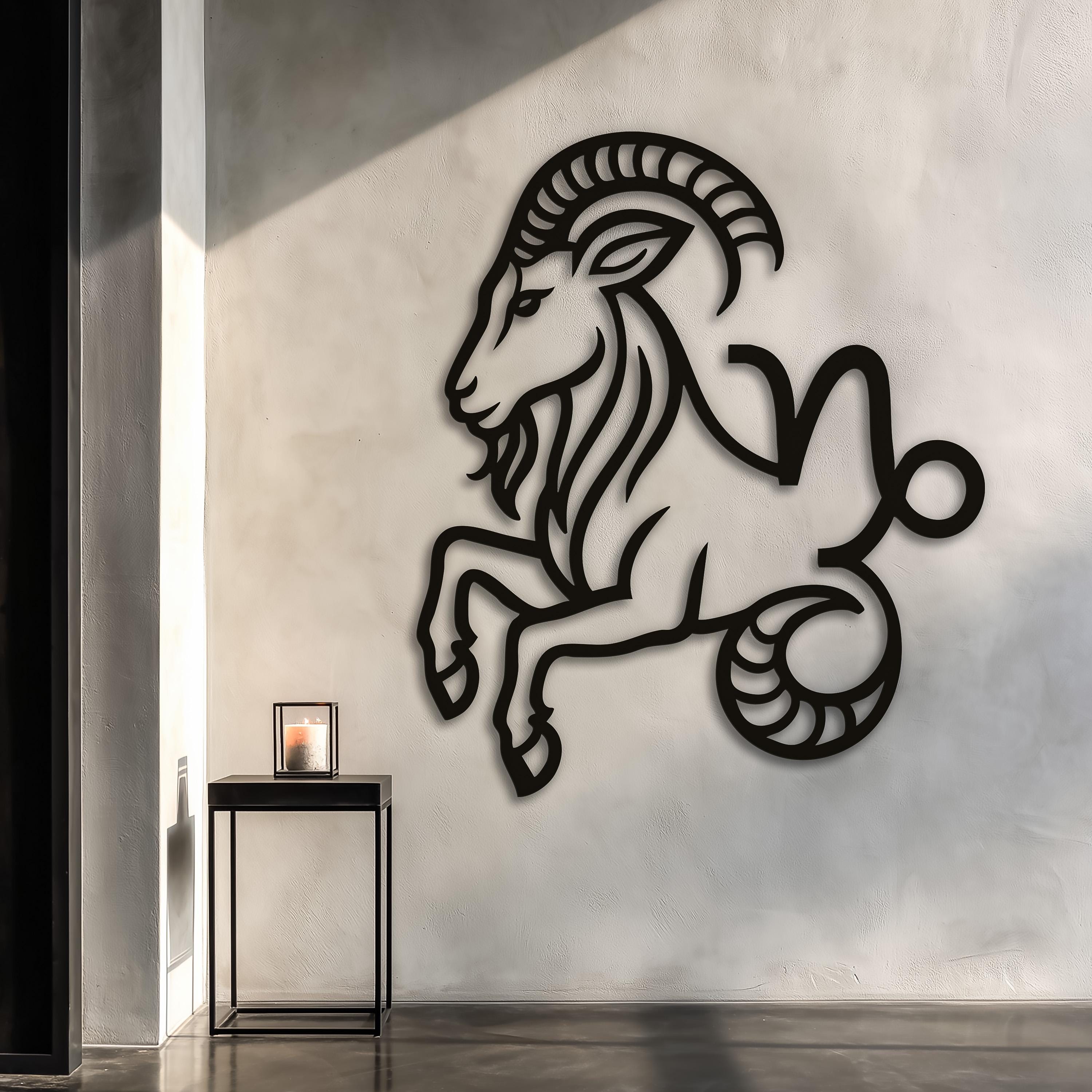 May include: A black metal wall art piece depicting the Capricorn zodiac symbol, featuring a stylized goat with curved horns and a fish-like tail. The design is a continuous, flat silhouette mounted on a plain wall above a wooden desk.
