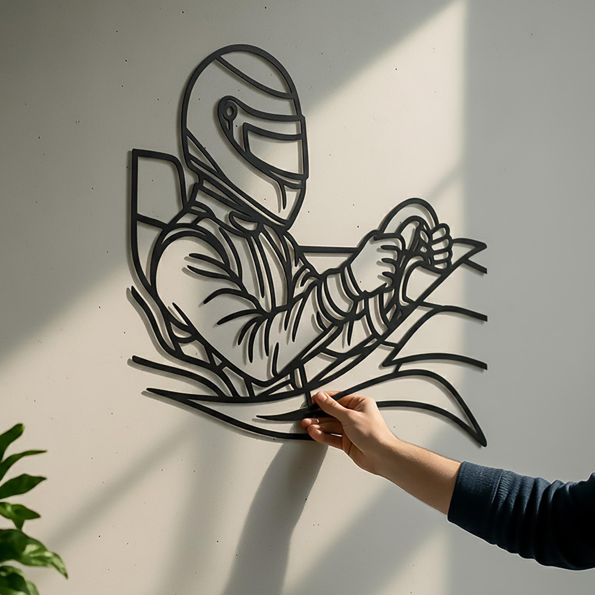 Close-up racing driver metal wall art with a hand touching the piece, proving real scale. CNC laser-cut matte black line art, premium powder coat, ready-to-hang. Oversized statement wall decor (1 m+ width) for motorsport fans, living room, office or man cave; great gift for car lovers.