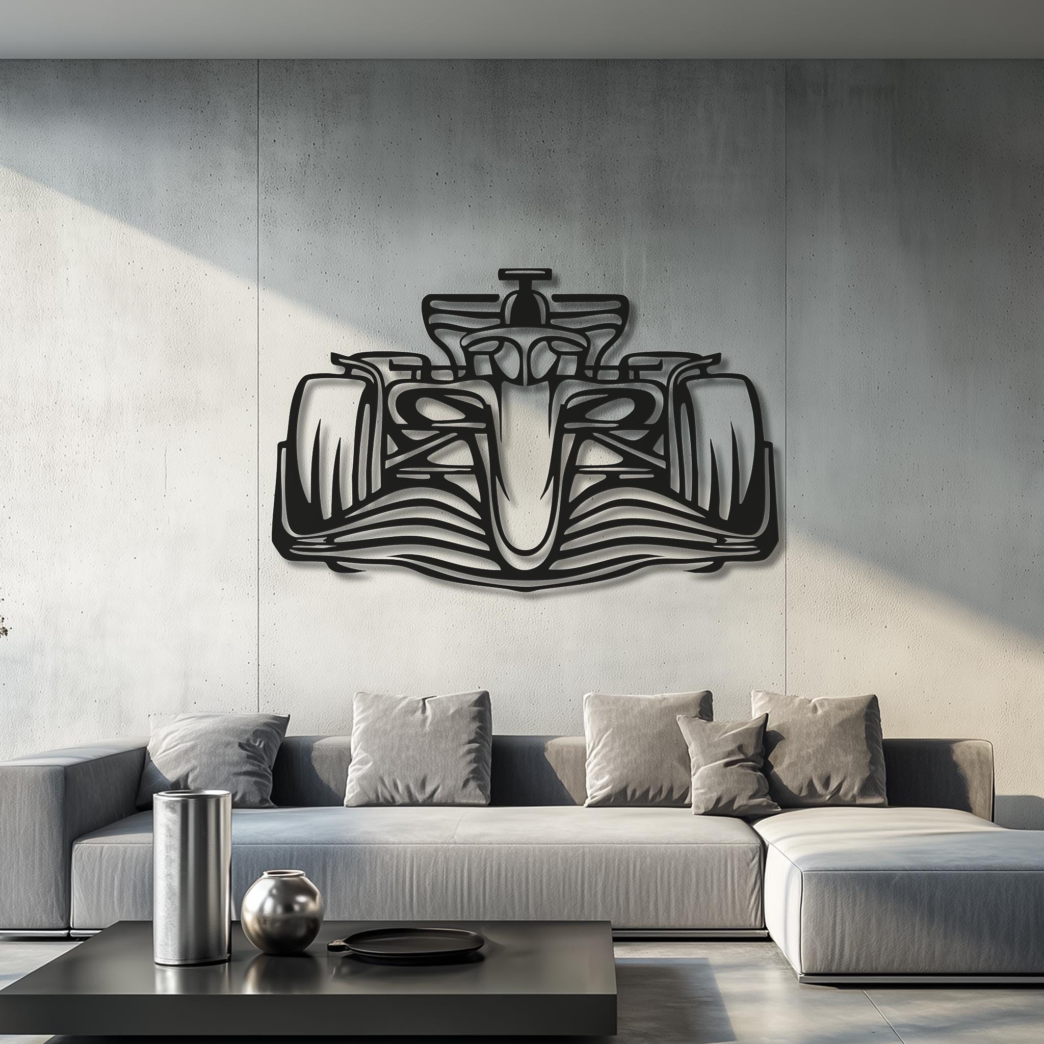 May include: A black metal Formula 1 race car wall art. The artwork is mounted on a gray concrete wall above a gray sectional sofa with several gray throw pillows. A modern living room setting.