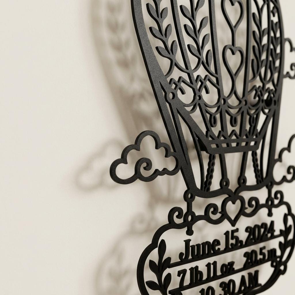 Close side detail of black powder coated metal birth stats sign showing raised 2 cm wall offset, shadow gap, laser cut hot air balloon lines, and nursery name sign depth on a light wall for realistic baby room decor.