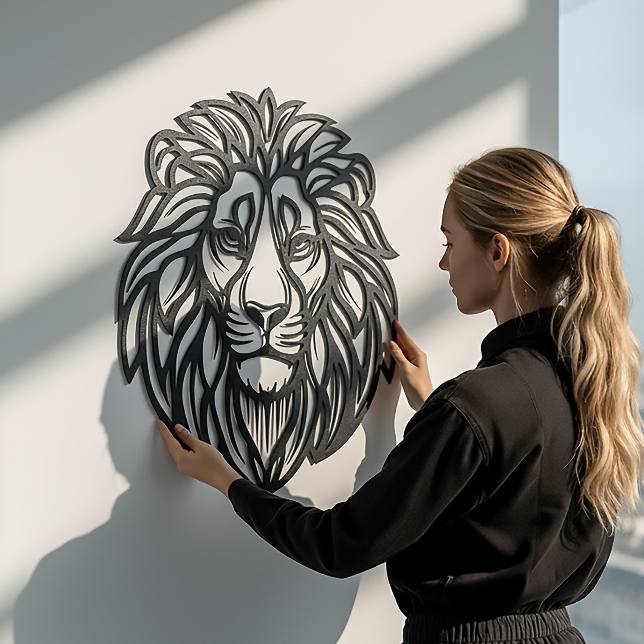 Real-life scale photo of lion metal wall art held by person. CNC laser cut, lightweight, easy to hang; matte black finish. Authentic image builds trust; great for living room or office; safari themed metal decor gift.