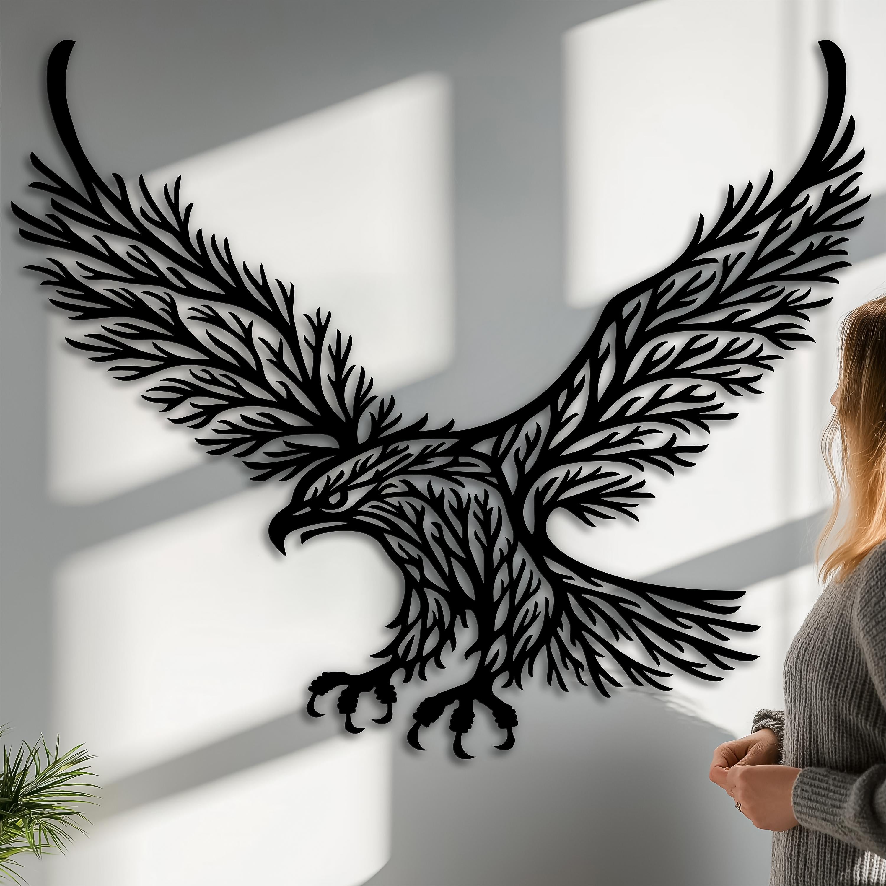 Eagle metal wall art in matte black steel, leaf-branch silhouette casting natural shadows