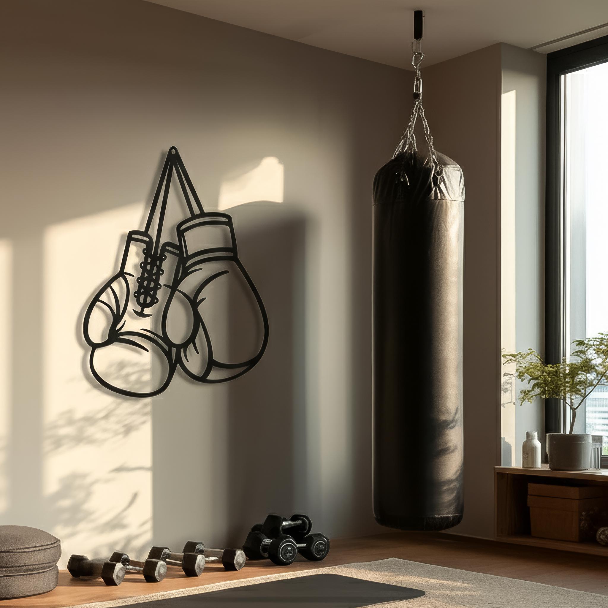 May include: A black metal wall art piece depicting a pair of hanging boxing gloves with visible laces and outlines. The design is minimalist and features a clean, continuous line structure, mounted securely against a light-colored concrete wall.