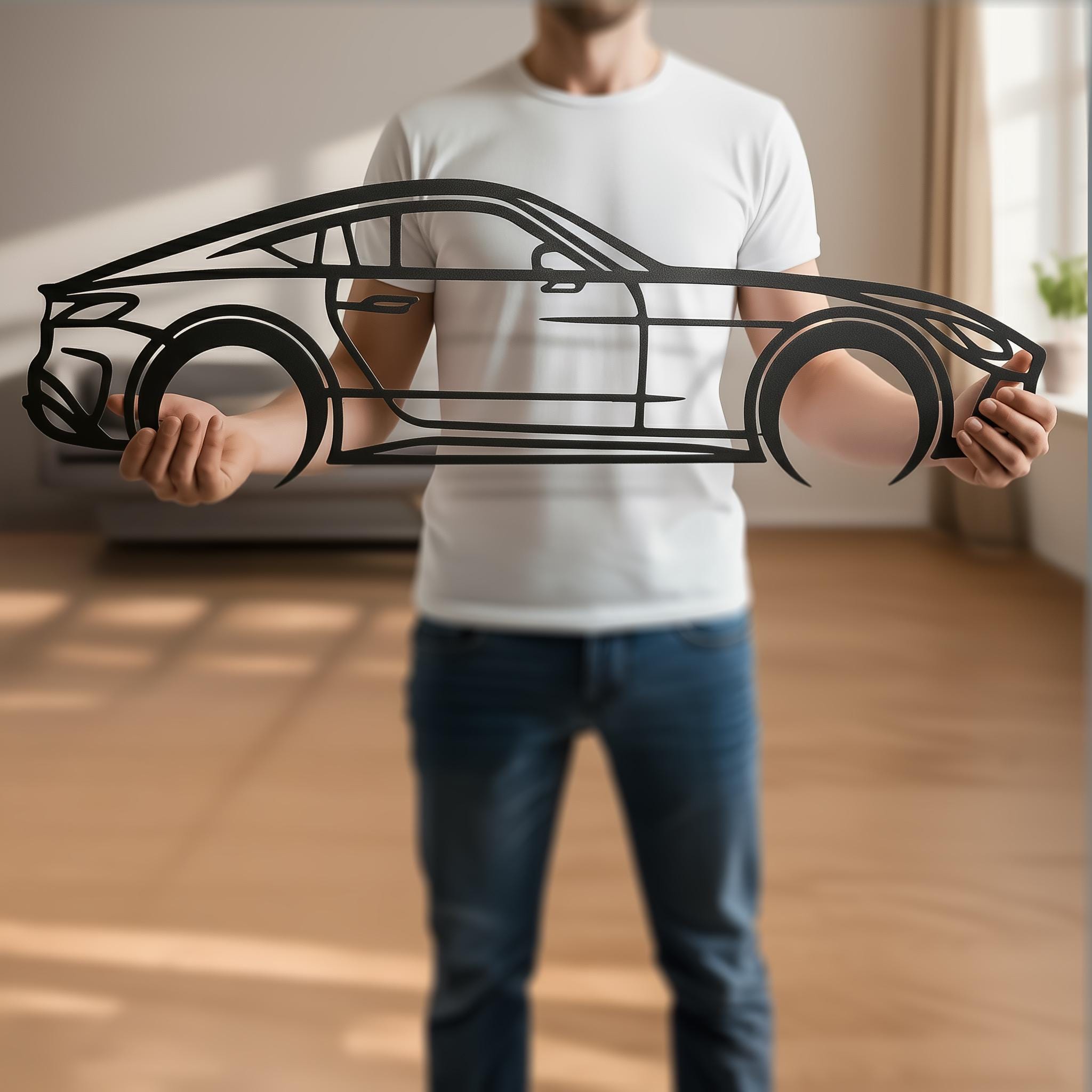 Real-life scale photo: man holding personalized car metal wall art, matte-black CNC cut, clean edges. Side-view coupe silhouette shows size and quality; custom name/plate/year available. Premium home office, garage or man cave decor; ideal gift for car lovers; square product image.
