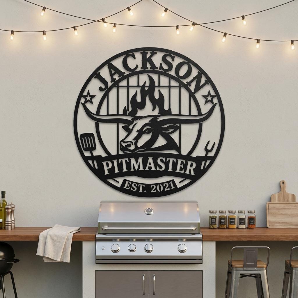 Custom BBQ sign displayed in a wide outdoor kitchen scene above a stainless grill, showing scale, circular layout, personalized name, pitmaster sign details and black metal backyard grill decor for scale and placement.